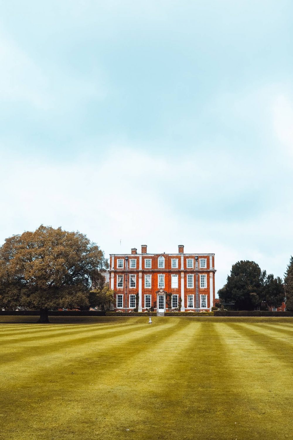 Side profile of Chichley Hall surrounded by grass and trees