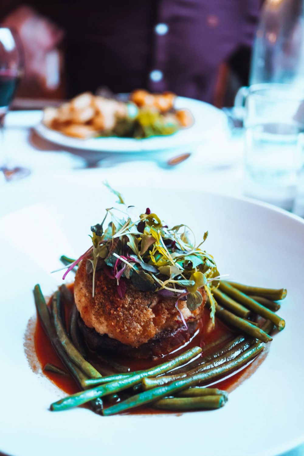 Braised shoulder of lamb topped with breaded vegetable mash surrounded by runner beans and a jus
