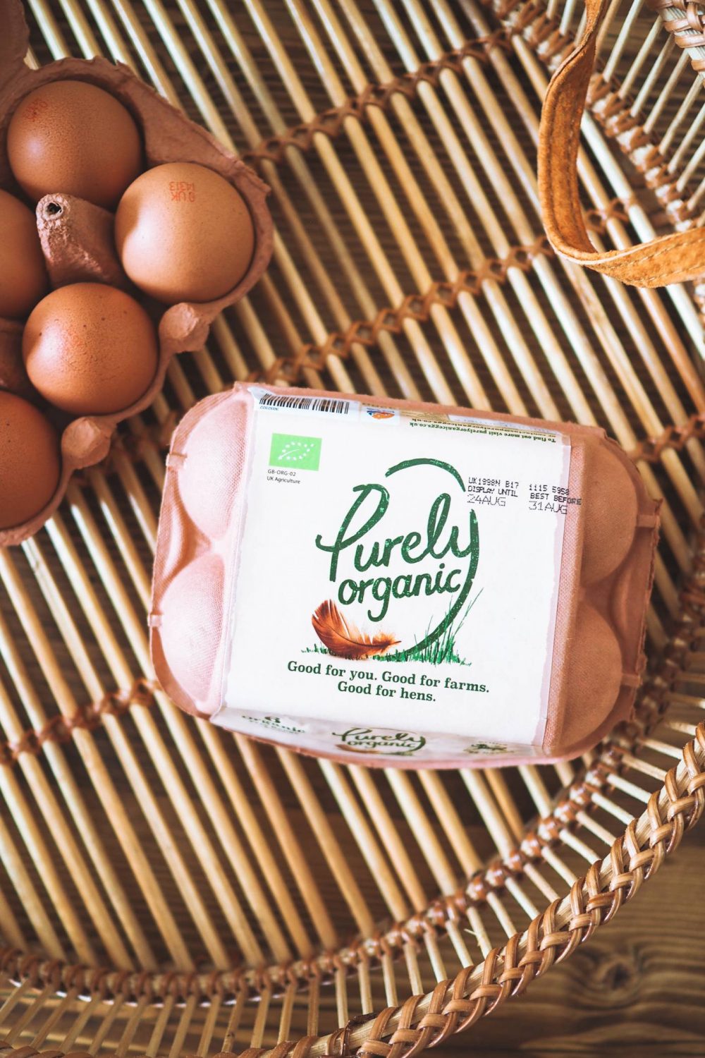 A flat lay image of a box of Purely Organic Eggs on a bamboo tray