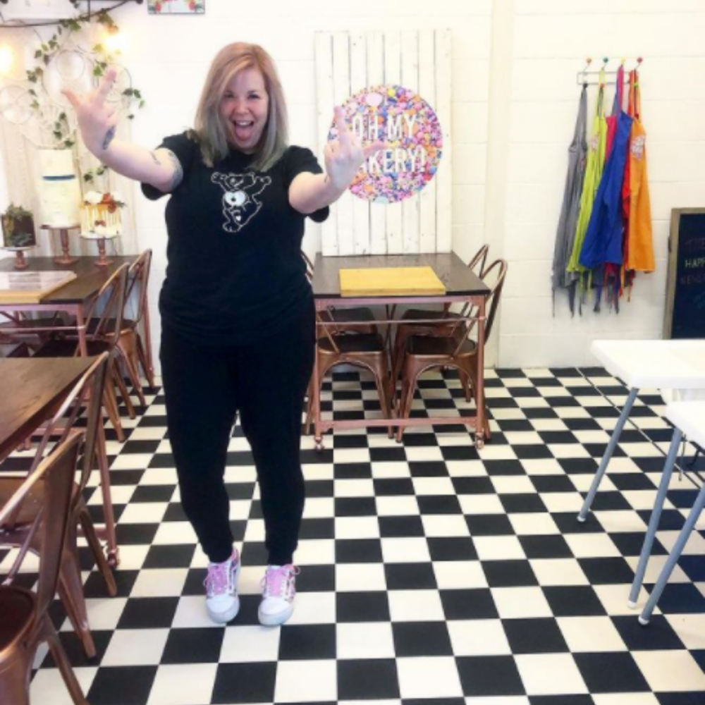 Kirsty Lund, Founder of Oh My Cakery standing in her cakery pointing at the camera.